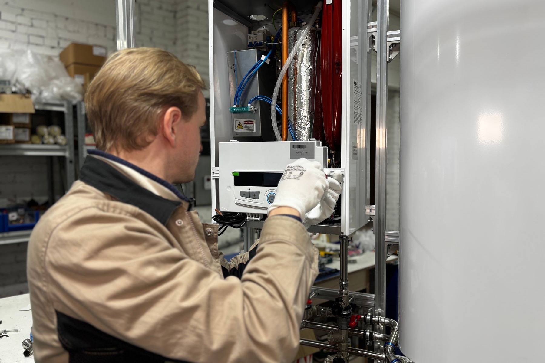 HVAC technician servicing a wall-mounted heating unit inside a customer home