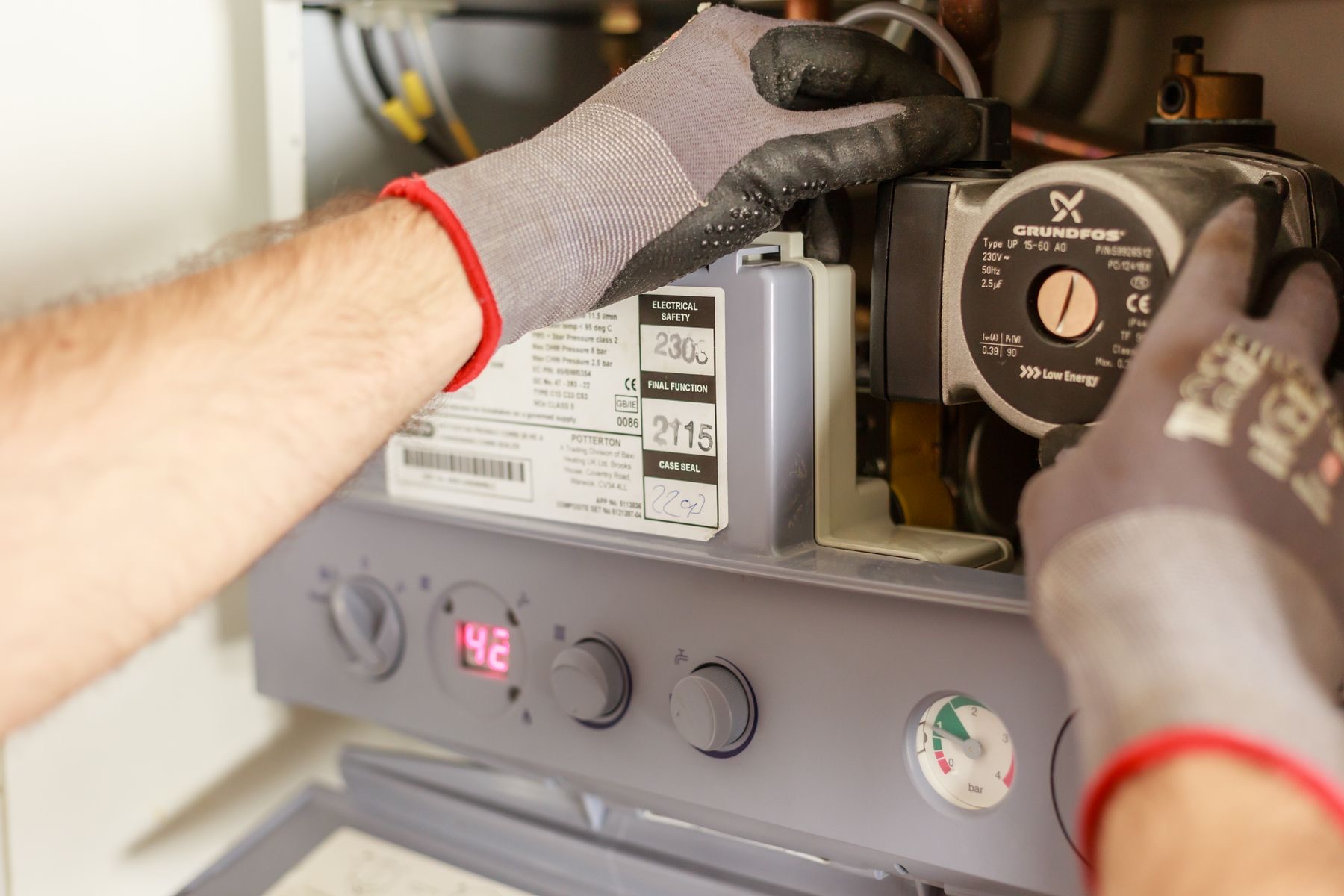 Gloved hands adjusting heating manifold valves during a maintenance visit